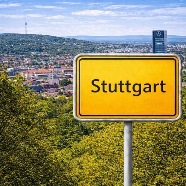 Gelbes Ortsschild Stuttgart mit Stadt im Hintergrund